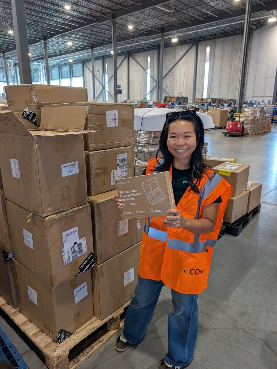 Leslie Chan holding Bare Ware inventory inside an Ecom fulfillment warehouse.