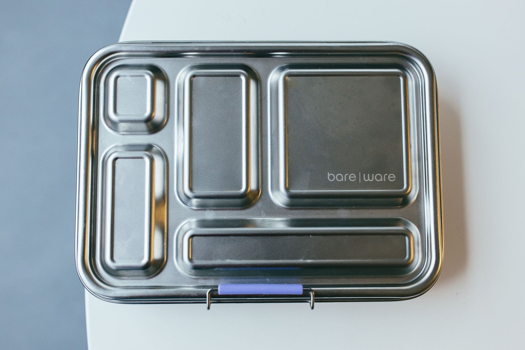 A closed Bare Ware five-compartment stainless steel lunch box viewed from above.